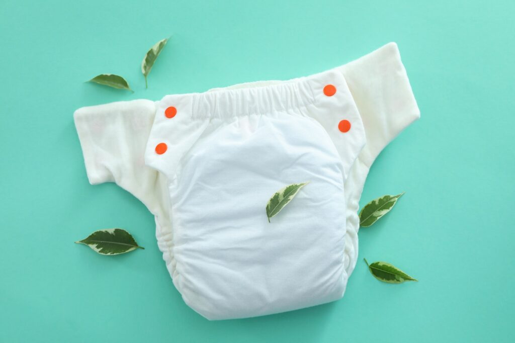 Concept of baby clothes with reusable diapers on mint background